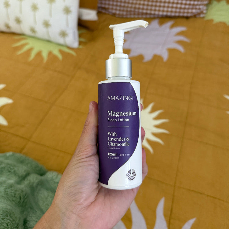 Hand holding a purple and white bottle labeled 'Amazing' against a patterned fabric background