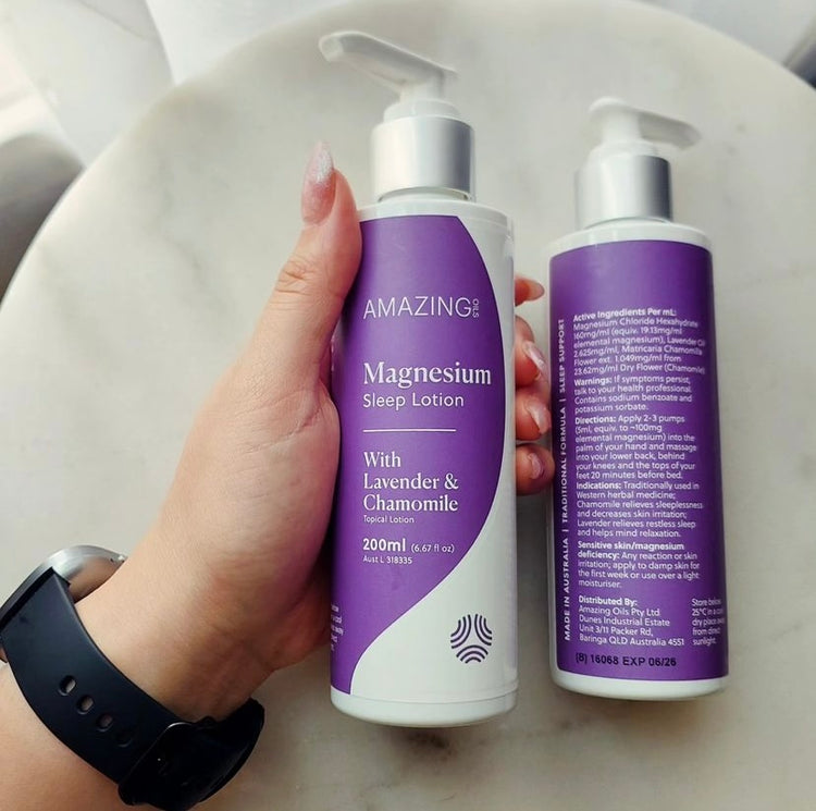 Hand holding a bottle of 'Amazing' magnesium sleep lotion with lavender and chamomile on a white background.