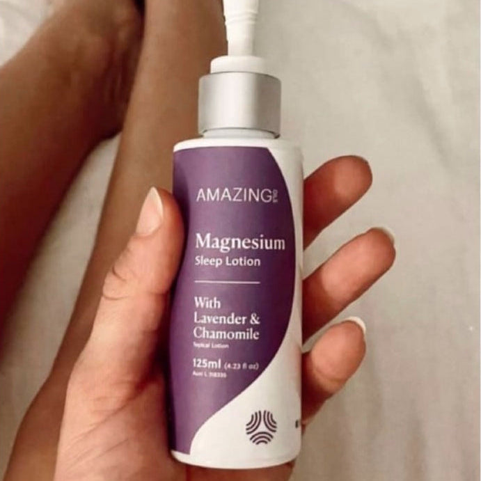 Hand holding a bottle of Amazing Oil Magnesium lotion with a blurred background